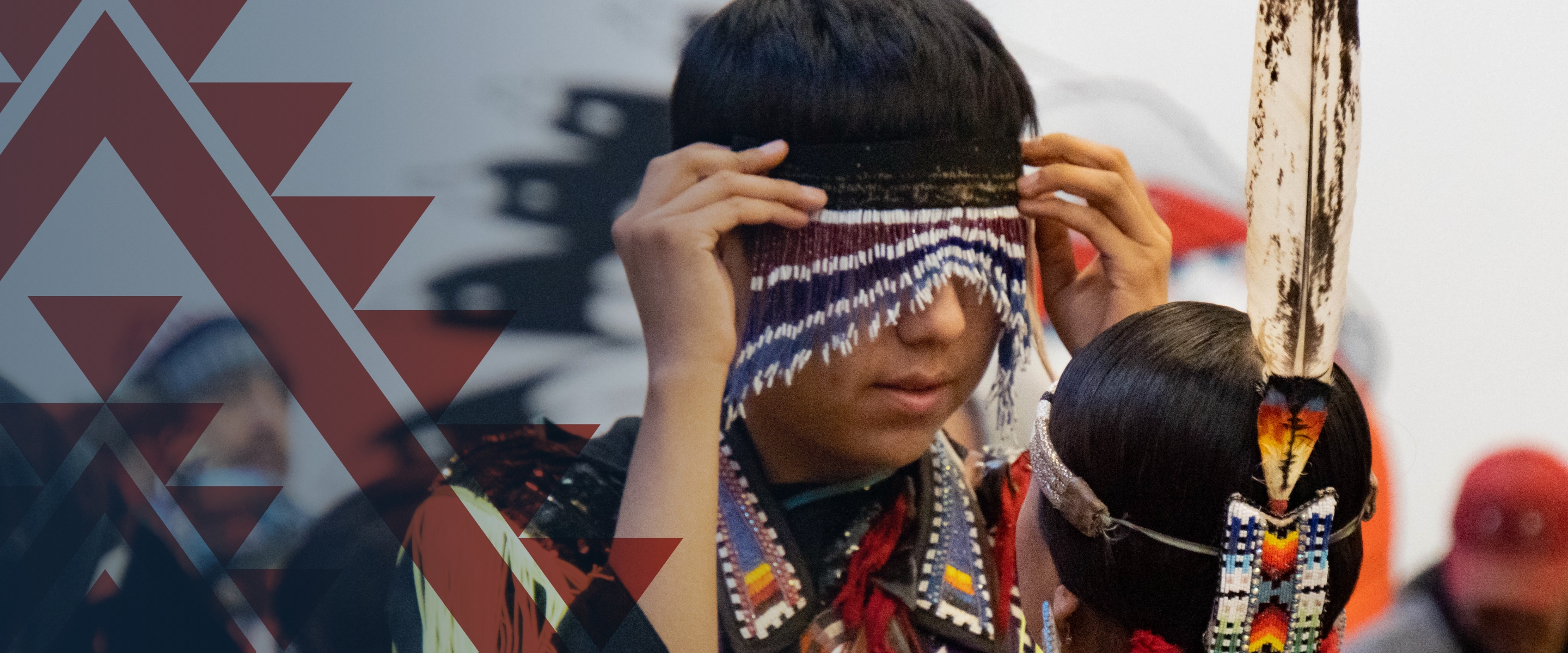 Native American youth adjusting his headdress at a Pow Wow