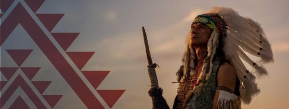 Native American adult male in full ceremonial dress looking off into the distance.