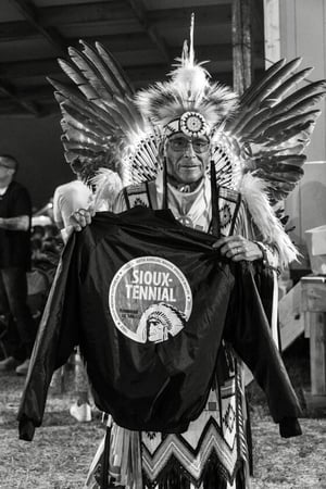 Image of older Native American man holding a jacket that says 